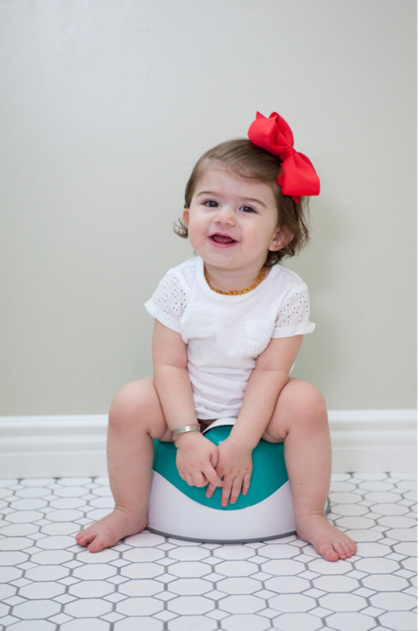 toddler sitting on training toilet